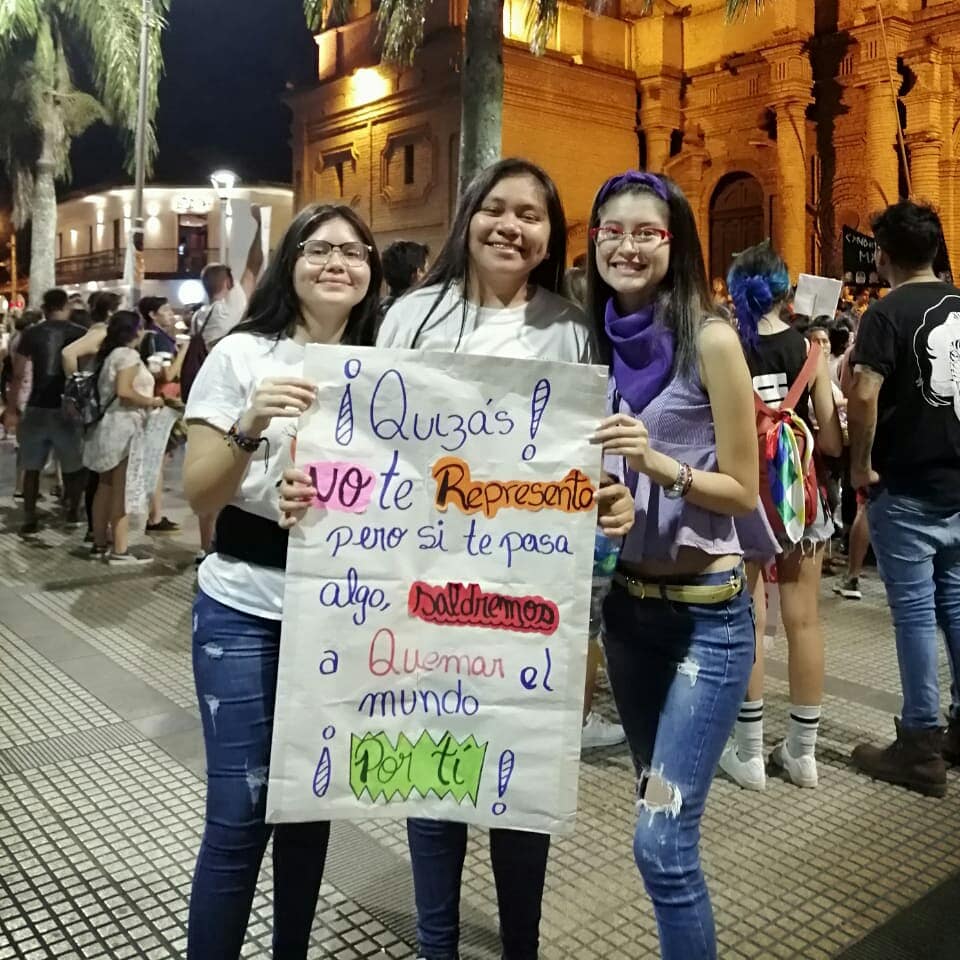 tres personas que tinene una pancarta hecha a mano que dice "Quizás no te represento pero si te pasa algo, saldremos a quemar el mundo por ti!"